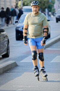 roller skater, roller blades, street, man, skater, outdoors, pavement, casual, bike lane, traffic, cars, urban